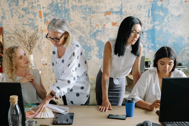Team collaborating on brand and marketing planning using laptops and design samples in a creative workspace.